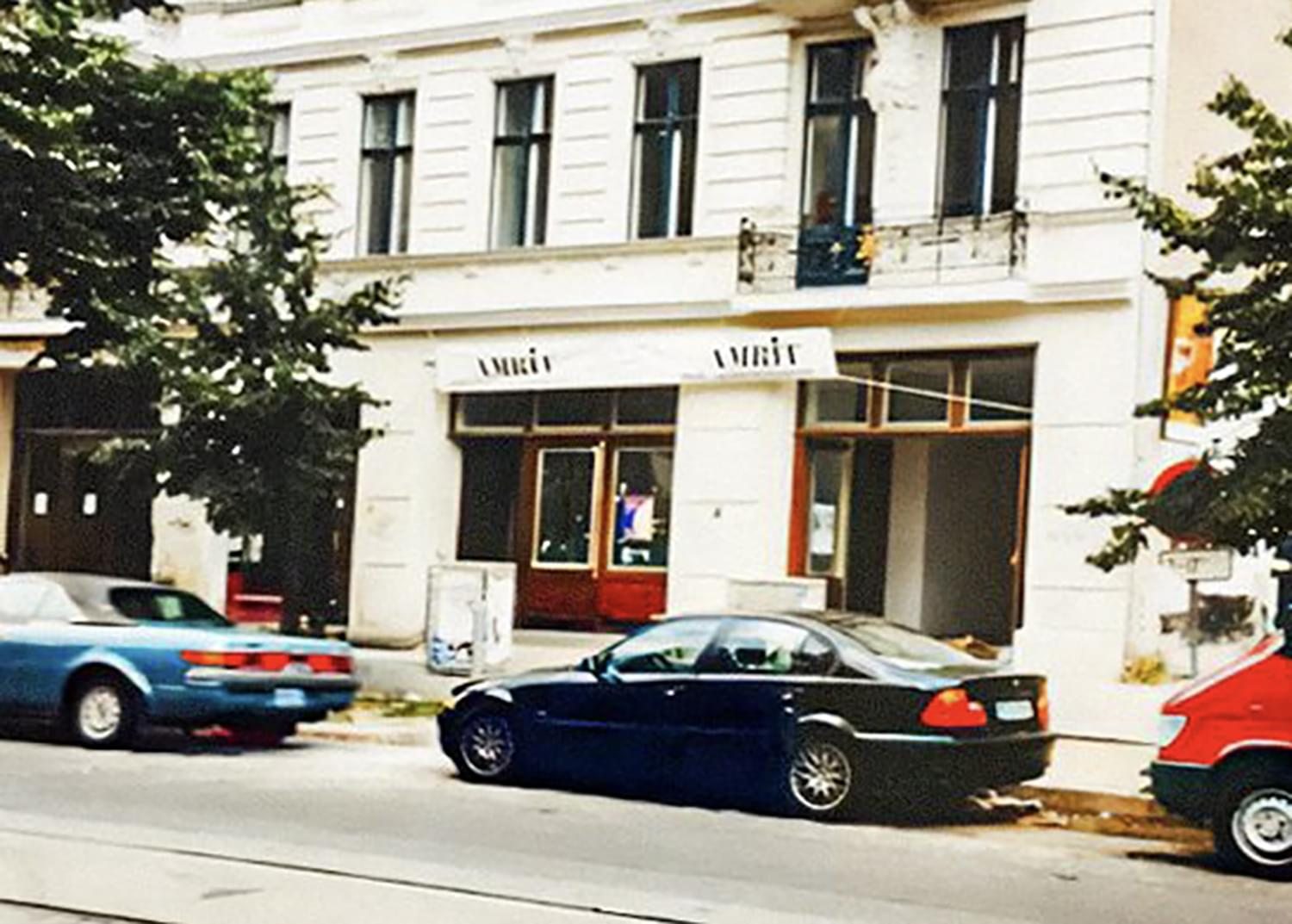 Oude foto van de witte gevel van AMRIT Mitte in 1999, met geparkeerde auto's ervoor